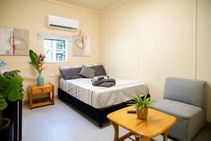 1 dormitorio con 1 cama, 1 silla y 1 mesa en Green Hills Accommodation Village, en Port Moresby