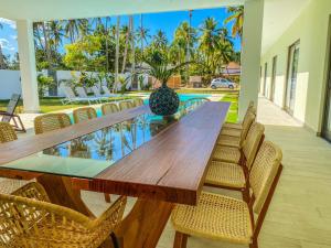 a wooden table and chairs on a patio with a pool at Villa Calma, luxury for big groups at the beach with large pool in Las Terrenas