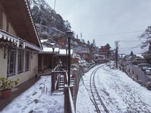una calle cubierta de nieve con una vía de tren junto a los edificios en Marigold Manor Homestay, en Darjeeling