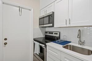 cocina con armarios blancos, fregadero y fogones en Comfy BNB w/ King Bed + Work/Travel + Beach 8 Min, en Hallandale Beach