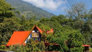 a red house with an orange roof in the forest at Hospedaje Rural Tupinamba in Ibagué