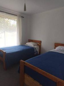 1 dormitorio con 2 camas y ventana en Casa de campo Llifén Futrono Lago Ranco, en Ranco