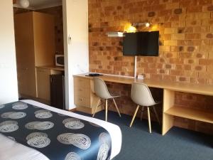 a room with a bed and a desk with two chairs at Werribee Park Motor Inn in Werribee