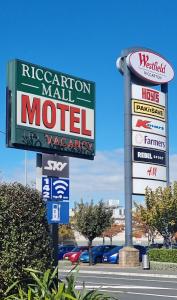 um sinal para um motel em frente a um concessionário de carros em Riccarton Mall Motel em Christchurch