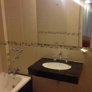 a bathroom with a sink and a tub and a mirror at Hotel San Carlos in Termas de Río Hondo