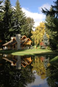 una casa con un reflejo en un estanque en Cabañas Ruca Kuyen Golf & Resort en Villa La Angostura