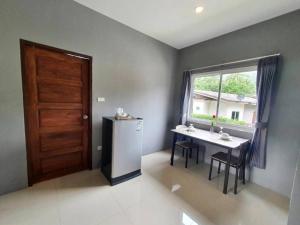 a kitchen with a table and a refrigerator and a window at Wanpratheep Village Kohphangan in Ban Madua Wan