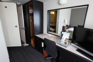 a room with a desk with a television and a mirror at Kagoshima Kuko Hotel in Kirishima