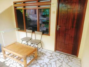 - une terrasse couverte avec 2 chaises et une porte en bois dans l'établissement Pandu Homestay Mandalika Lombok, à Kuta Lombok