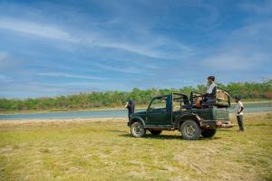 a green jeep parked in a field next to a river at Green Chwadi Nature Retreat in Kawasoti