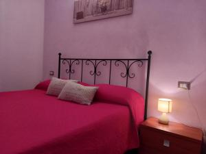 una camera da letto con un letto con una coperta rossa e una lampada di asfodelo a Villaputzu