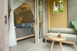 a bedroom with a bed and a couch and a table at Ubad Retreat in Ubud