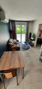 a living room with a table and a couch at Le Nid'Isle - Stationnement privé gratuit - Wi-Fi performant - Climatisation in LʼIsle-sur-la-Sorgue