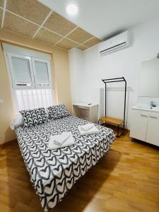 a bedroom with a bed with a black and white comforter at Hospedaje Puente de Vallecas in Madrid