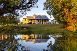 a house on a hill with a reflection in the water at Ratho Farm in Bothwell