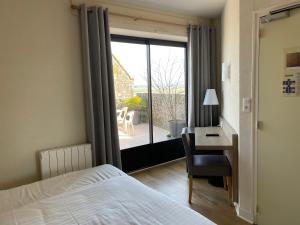 a bedroom with a bed and a desk and a window at La Vieille Auberge in Le Mont Saint Michel