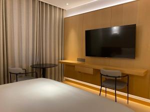 昌原市にあるHotel Avenueのテレビと椅子2脚が備わるホテルルームです。