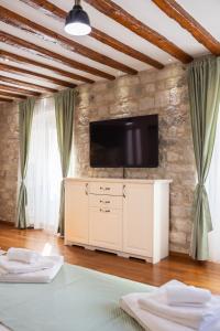 a living room with a tv on a stone wall at Stephane City Vibe Suites in Trogir