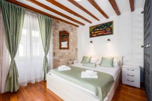 1 dormitorio con cama blanca y almohadas verdes en Stephane City Vibe Suites en Trogir
