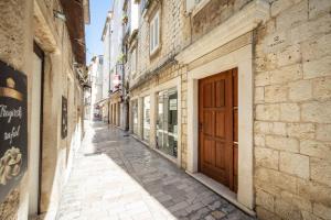 eine leere Gasse mit Gebäuden und einer Holztür in der Unterkunft Stephane City Vibe Suites in Trogir