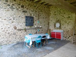 a room with a table and chairs in a stone wall at La Bicyclette Bleue in Montpinchon