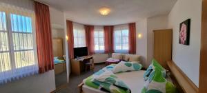 a bedroom with a bed and a desk and windows at Landhaus Adorf in Bad Elster