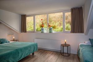 a bedroom with two beds and a window with two candles at Castle View 2 in Valkenburg