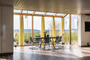 a dining room with a table and chairs and large windows at Ruhige Ferienwohnung mit Panoramablick in Ingoldingen