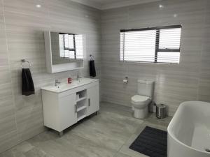a bathroom with a sink and a toilet and a mirror at Idiaz Beach House in Mossel Bay