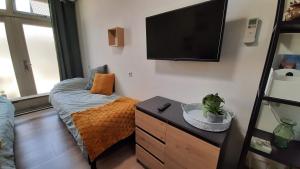 a bedroom with a bed and a flat screen tv at Gastenverblijf Nummer 1 Sommelsdijk in Sommelsdijk