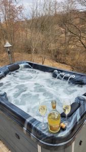 una bañera de hidromasaje con 2 copas de vino en Mountain cottage en Parád