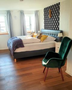 a bedroom with a large bed and a green chair at Schatzbergalm Pension in Dießen am Ammersee