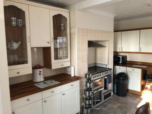 uma cozinha com armários brancos e um forno com placa de fogão em 3-Bed House Waterfall country Brecon Beacons em Pont-Nedd-Fechan