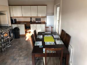a kitchen with a table and chairs and a kitchen with white cabinets at 3 Bed House - Sleeps 6 - Parking - Garden - WIfi in Pont-Nedd-Fechan +8 photos