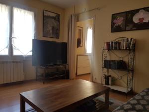 a living room with a tv and a wooden coffee table at Charmante maisonnette 2 personnes climatisée in Surgères