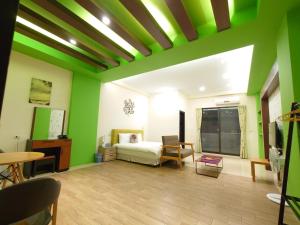 a bedroom with green walls and a bed and a table at Cat Mia Hostel in Hualien City