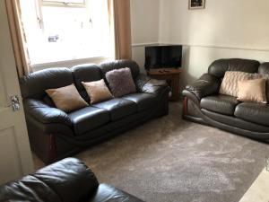 a living room with a leather couch and a television at 3br-Sleeps6-Garden-Mountain &near 4 Falls Walks on in Pont-Nedd-Fechan