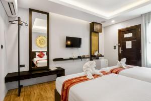 a hotel room with two beds and a mirror at Paraiso Hotel Chiangmai in Chiang Mai
