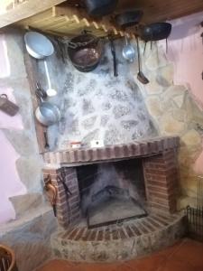 a stone fireplace with pots and pans hanging over it at La casita del herrador in El Burgo de Osma