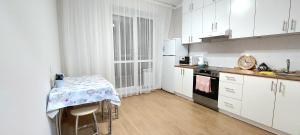 a kitchen with white cabinets and a table in it at Будапешт 197 in Prigorodnyy