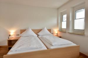 um quarto com 2 camas com lençóis brancos e 2 janelas em Hotel Kranz em Gottmadingen