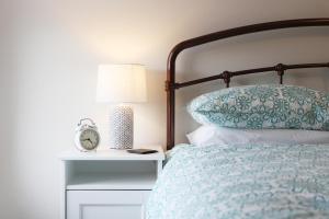 a bed with a pillow and a clock on a night stand at Ellinbrook Guest House in Hunstanton