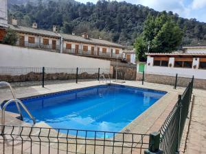 a large blue swimming pool with a fence around it at Apartamentos El Portillo in Arroyo Frio