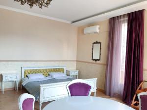 1 dormitorio con 1 cama con sillas moradas y mesa en Hotel Gallery, en Tiflis