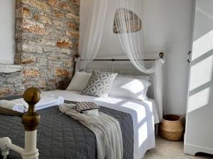 a bedroom with a bed and a stone wall at PETRA HOME heritage and hospitality in Apeiranthos