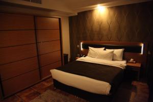 Schlafzimmer mit einem großen Bett mit einem Kopfteil aus Holz in der Unterkunft Merci Hotel Erbil in Erbil