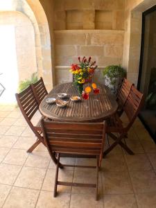 drewniany stół z krzesłami i kwiatami na patio w obiekcie Ad Hoc B&B w mieście Il-Pergla