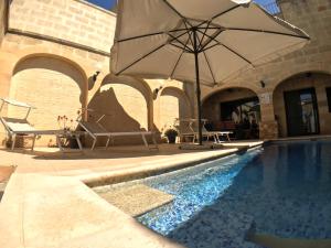 an umbrella and chairs next to a swimming pool at Ad Hoc B&B in Il-Pergla