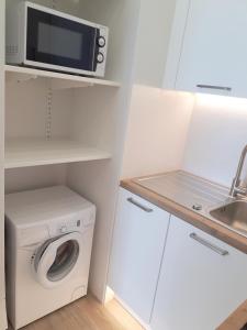 eine Küche mit einer Waschmaschine und einer Mikrowelle in der Unterkunft Magnifique Studio Face Mer avec Place Privative. in Saint-Jean-de-Monts