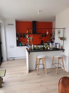 een keuken met een oranje muur en twee krukken bij VERADEMING in Bilzen